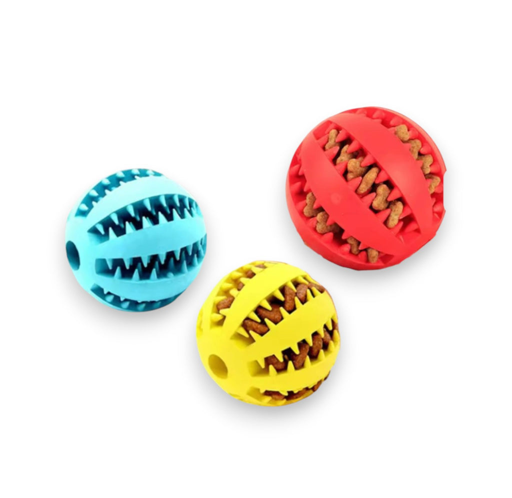 Three colorful rubber treat-dispensing pet balls in blue, red, and yellow, with visible kibble inside two.