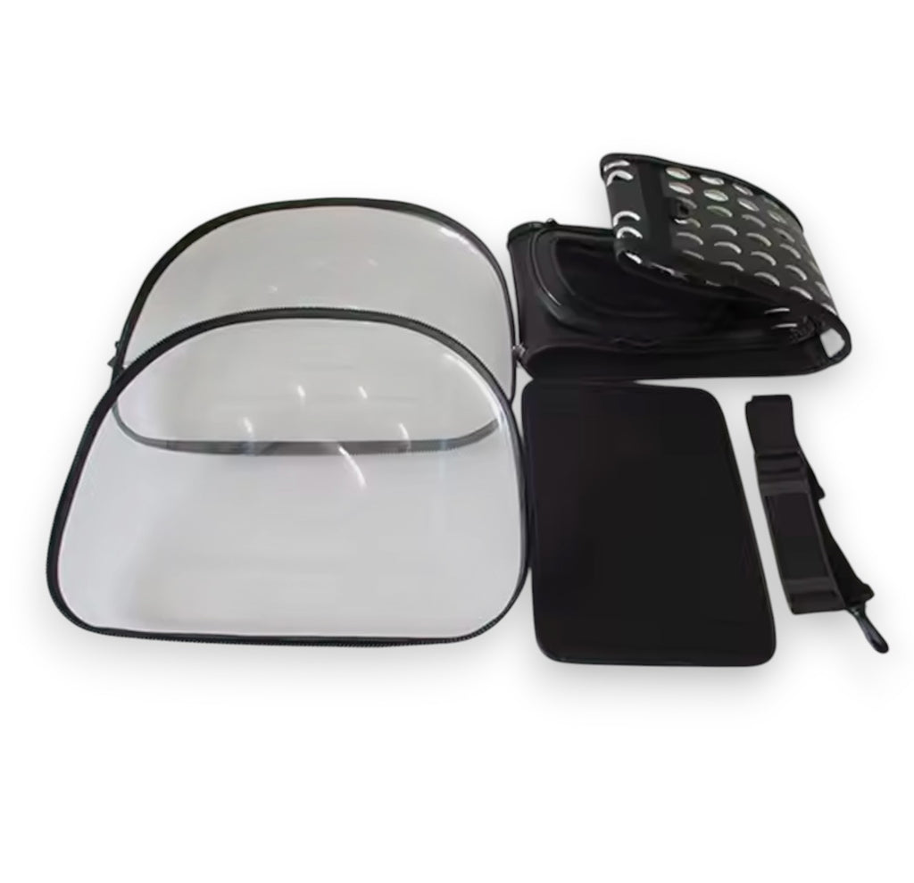 Disassembled black and clear portable pet carrier with transparent plastic panels, a ventilated fabric top, and a strap.