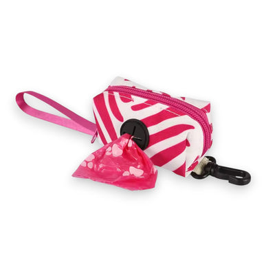 Pink and white zebra-striped fabric dispenser for dog waste bags with a pink paw print bag emerging, black clip.
